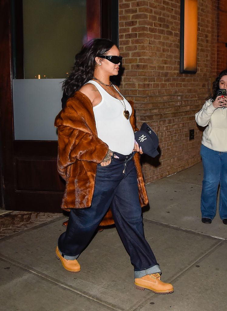 Rihanna wearing a fur coat, white vest and baggy jeans