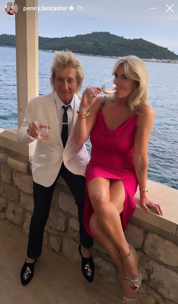 Penny Lancaster e Rod Stewart bebendo uma taça de vinho à beira-mar
