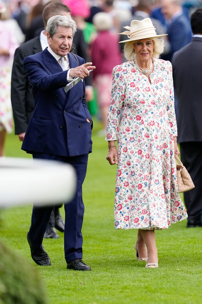 Queen Camilla in floral dress talking to a man