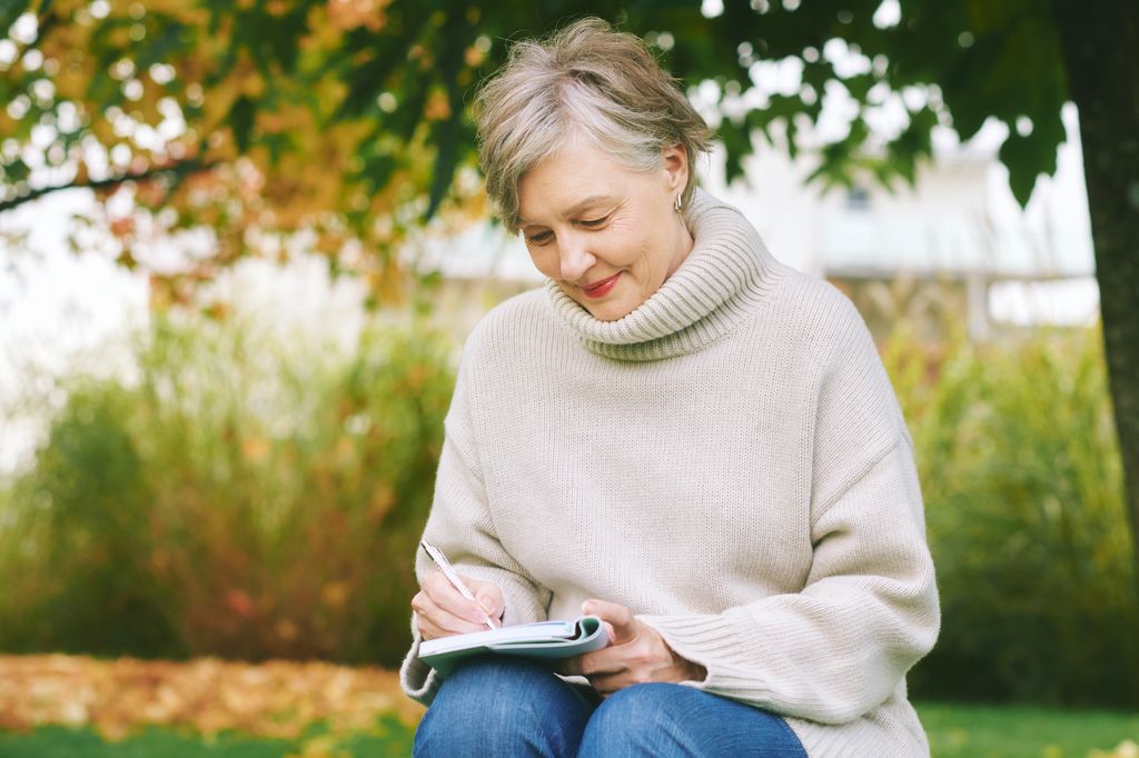 woman writing in journal outdoors to get over heartbreak