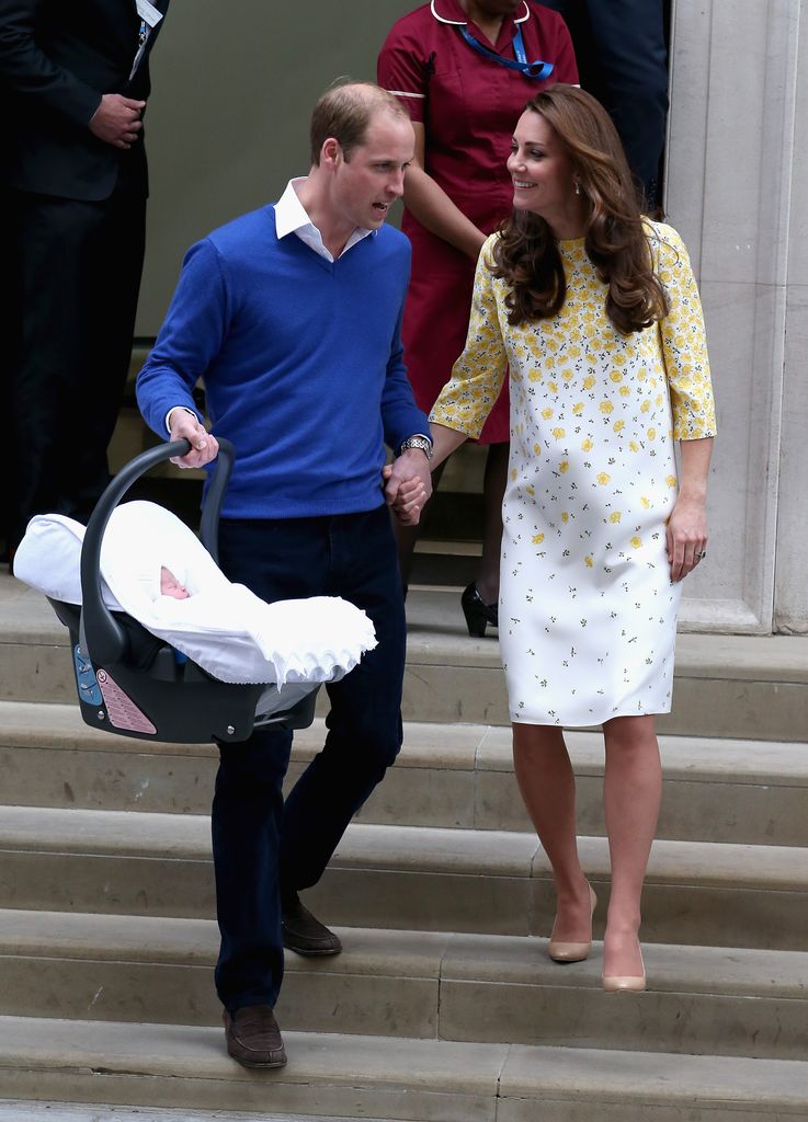 William holds wife Kate's hand after they leave hospital with baby Charlotte