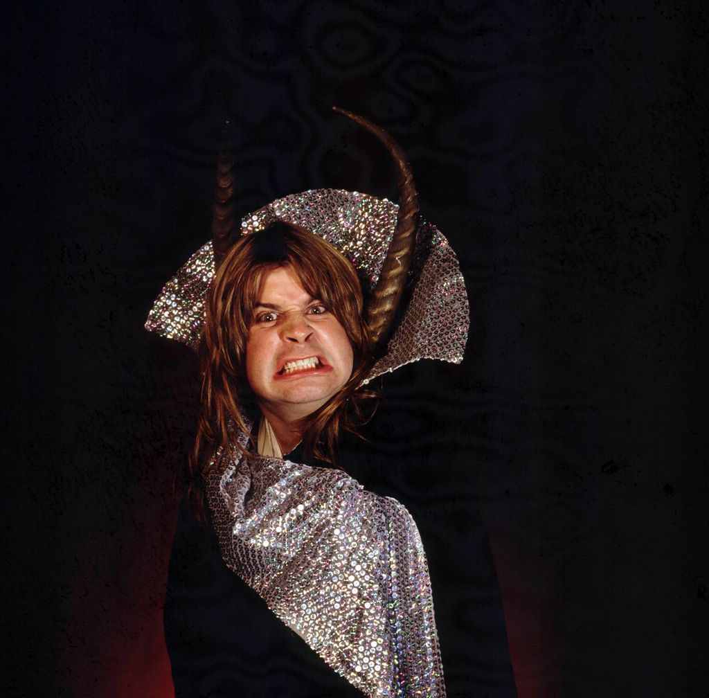 Ozzy Osbourne in a photoshoot with a long black cloak and horns