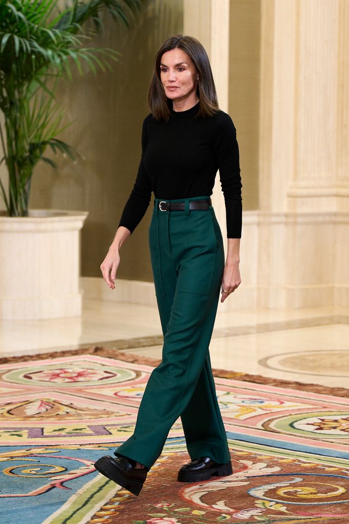 Queen Letizia of Spain walking and wearing green trousers, black jumper and chunky black loafers