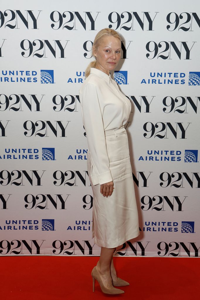 Pamela Anderson on red carpet in white pencil skirt and white shirt