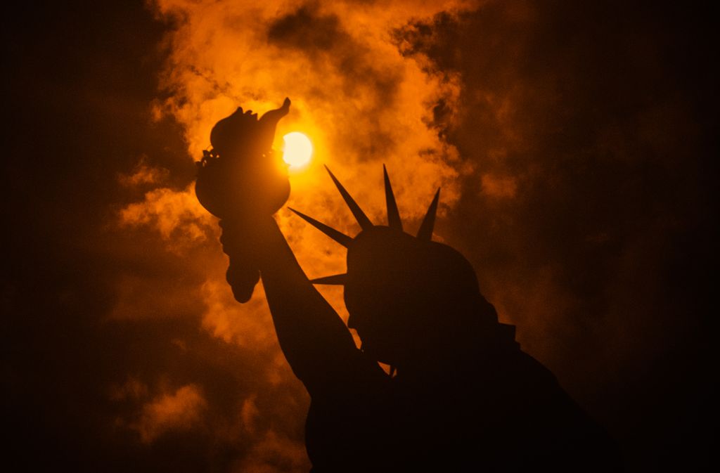 The solar eclipse is seen behind the Statue of Liberty at Liberty Island in on August 21, 2017 in New York City