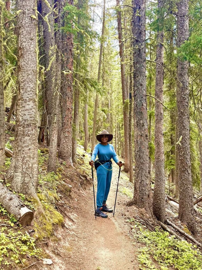 Oprah looking fit with walking sticks standing in a forest