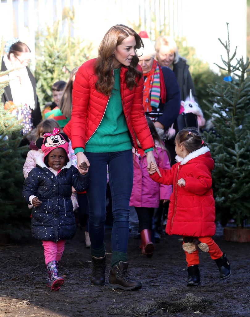 Kate holds hands with children at Christmas tree farm