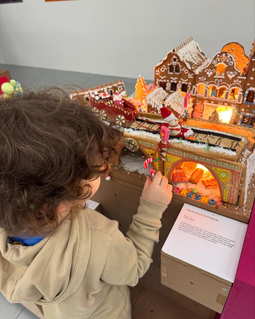 young boy admiring gingerbread house display