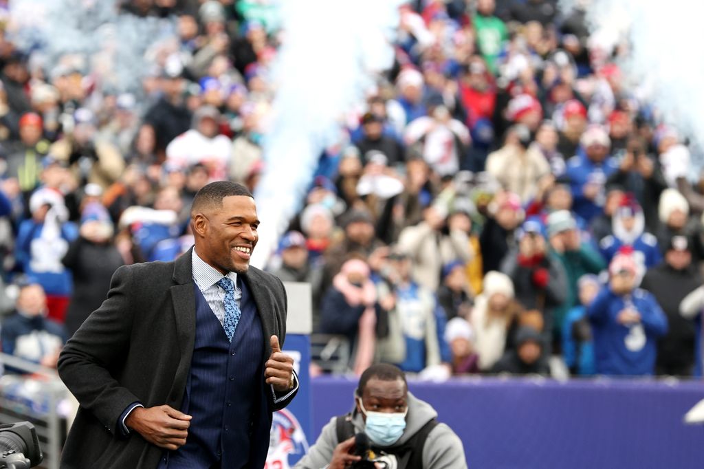 Former New York Giants player Michael Strahan jogs onto the field during the ceremony to retire his number at half time of the game between the Philadelphia Eagles and the New York Giants at MetLife Stadium on November 28, 2021 in East Rutherford, New Jer