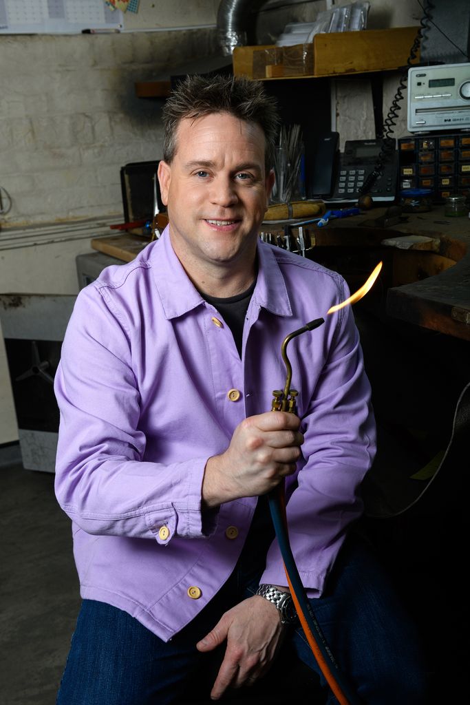 Richard Talman holding a fire tool in his workshop