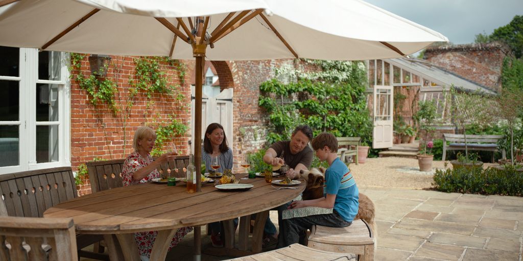 jamie oliver with mum, wife and son eating at outside table at home