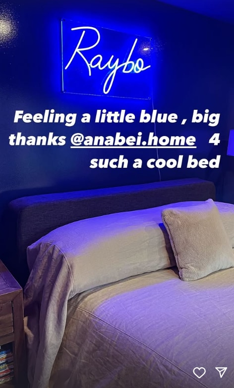 Dark blue bedroom with neon light reading Raybo