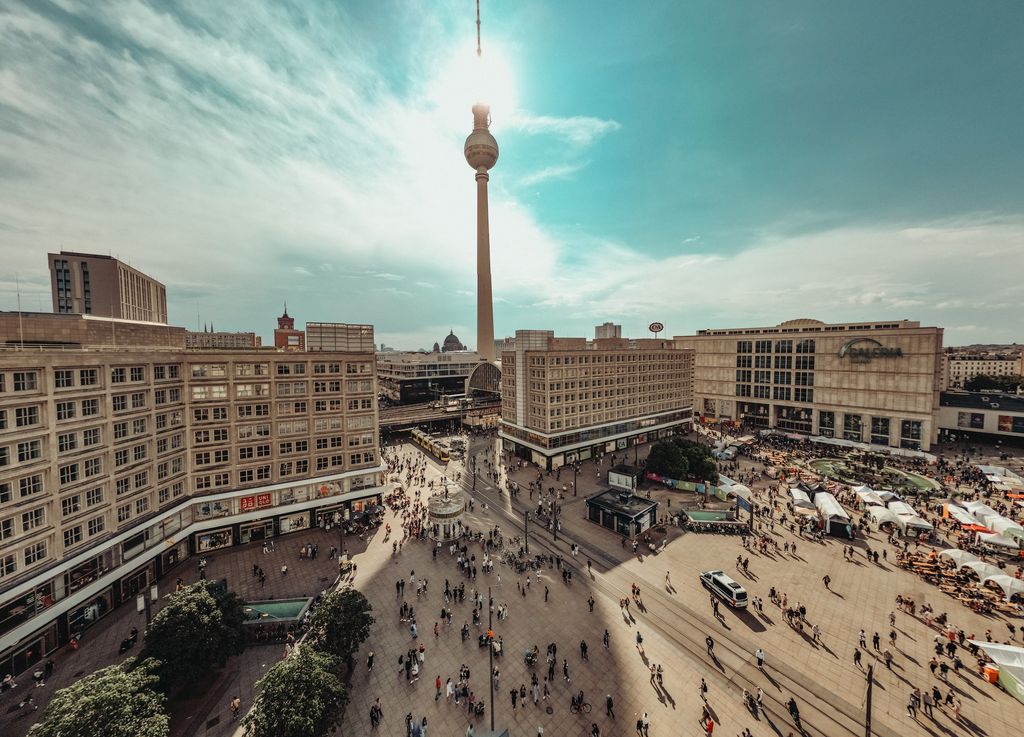 The Fernsehturm TV Tower stands as a sentinel above Berlin's Alexanderplatz, the city's urban heartbeat. This image offers an aerial snapshot of Germany's tallest building alongside the bustling public square, encapsulating the essence of Berlin.