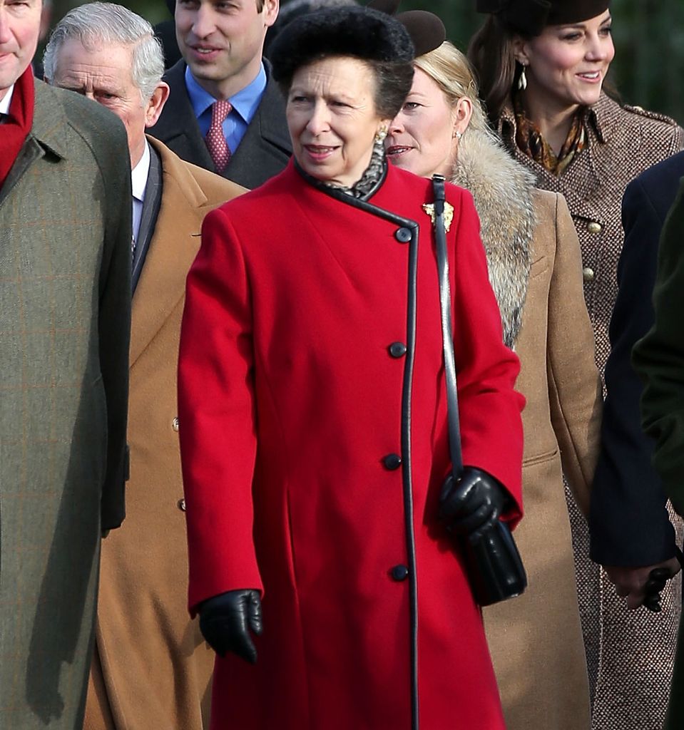Princess Anne in a red coat outside with the royal family