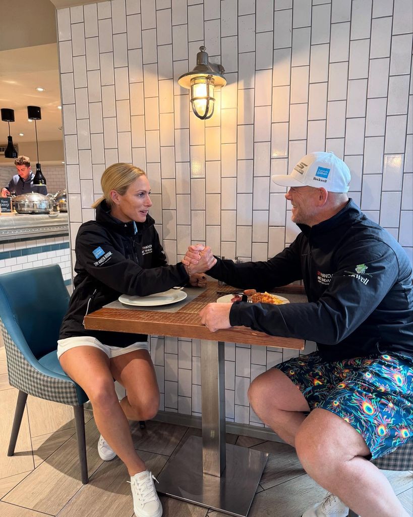Zara and Mike Tindall holding hands over a table 