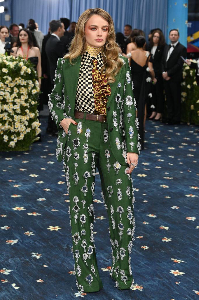 Joey King wears a green suit covered in embellished details teamed with a checkerboard shirt and patterned tie.