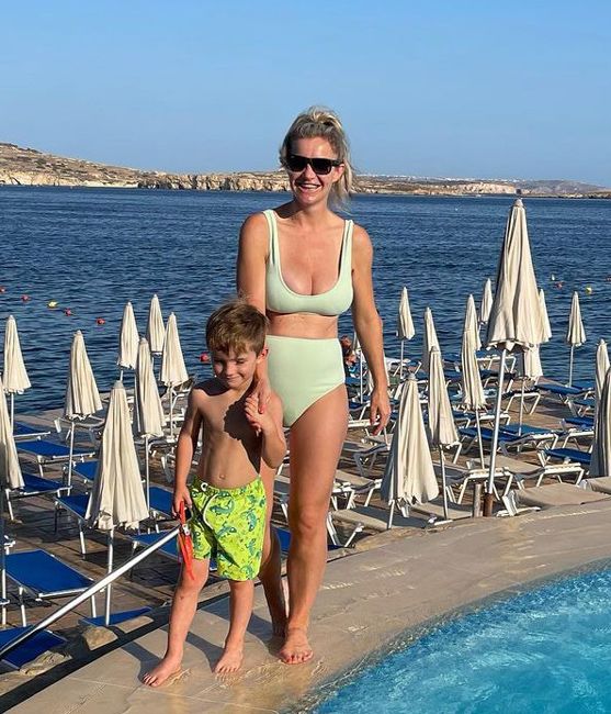 helen poses by the pool with a little boy in a light green bikini