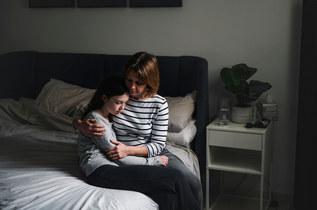 A mature woman comforts her teenage daughter