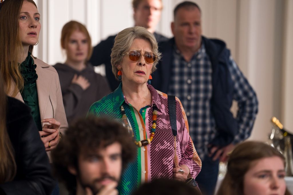 woman wearing glasses and colourful shirt standing in room full of people