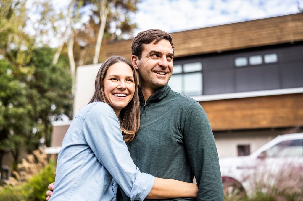 Portrait of married couple in front of modern home