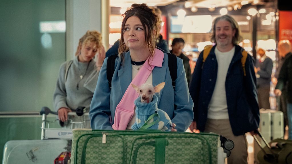 woman pushing suitcase trolley with small dog on topthrough airport