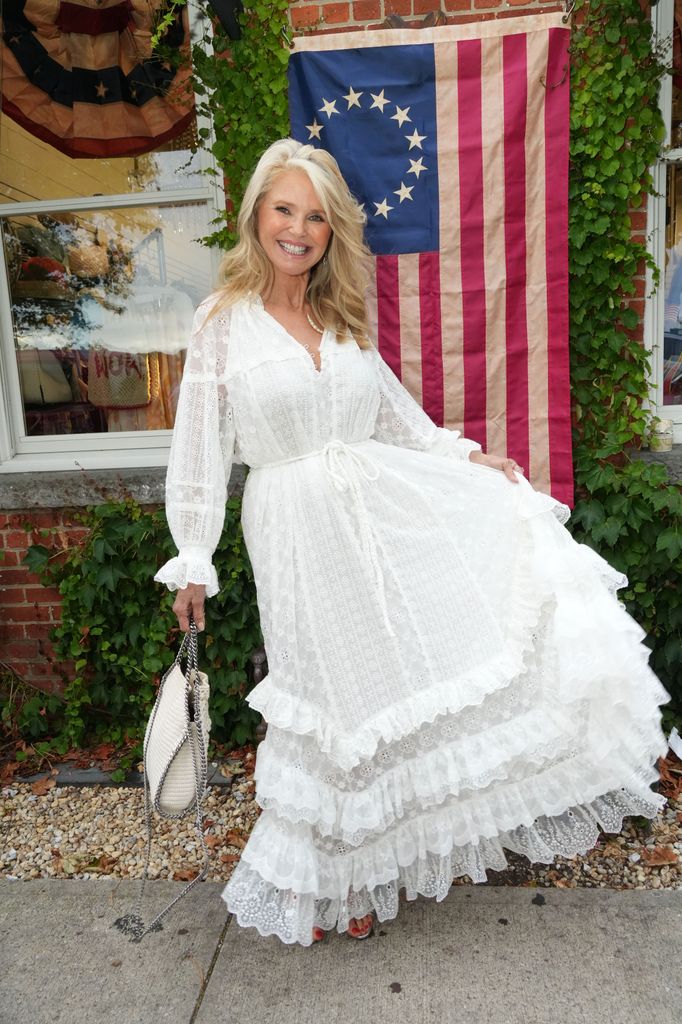 Christie Brinkley shows off white dress with US flag behind her