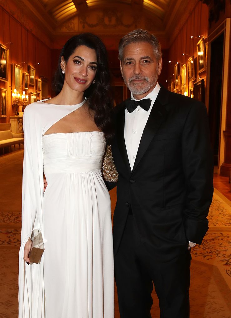 Amal Clooney in a white dress and George Clooney in a suit