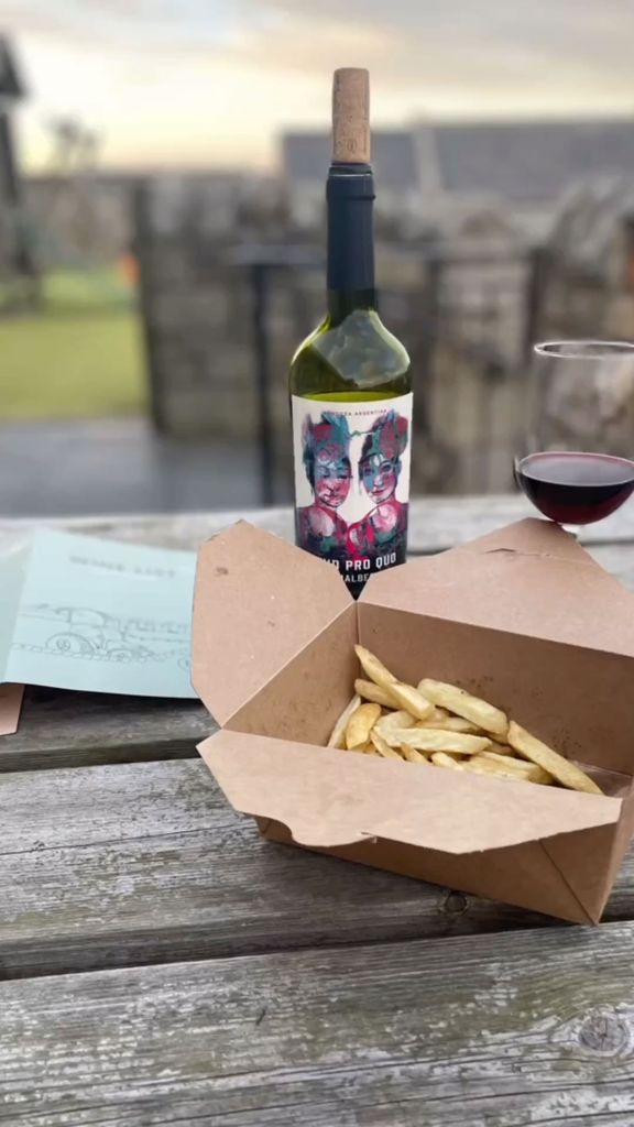 box of chips and bottle of red wine on wooden table 