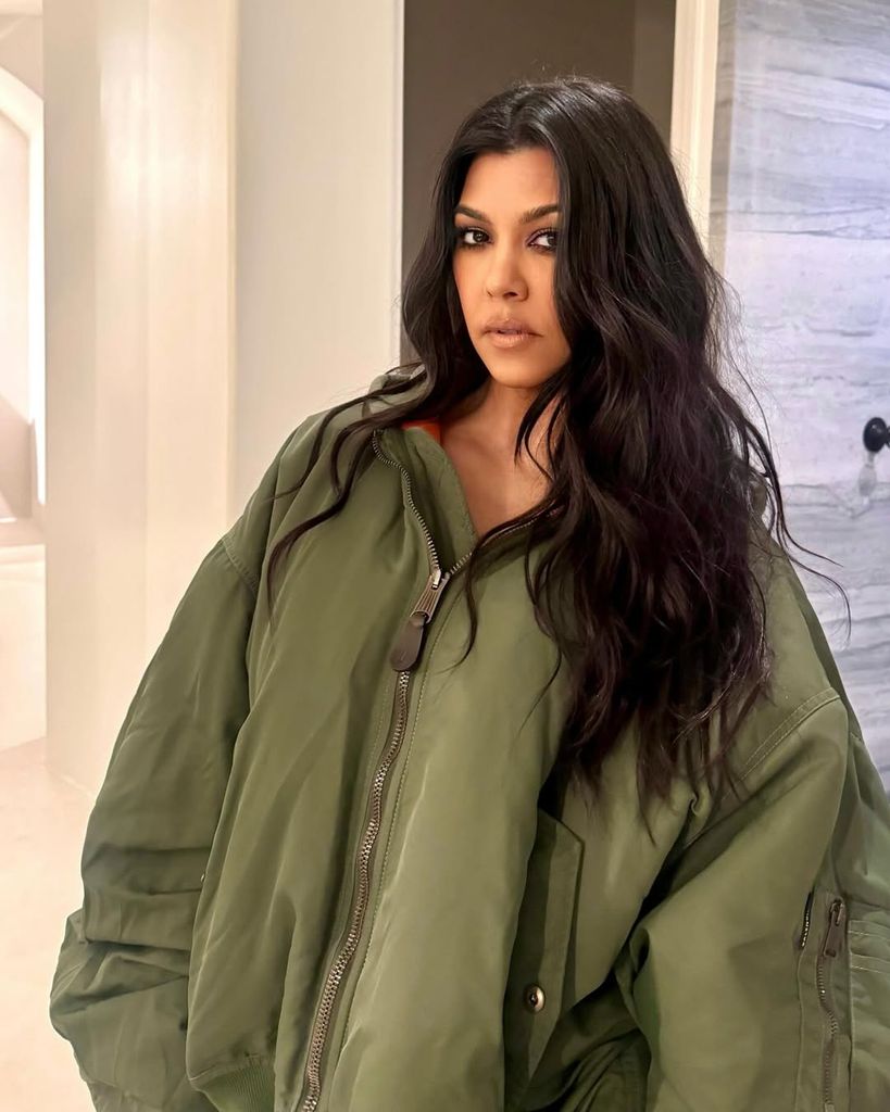 Kourtney Kardashian posing for a photo wearing oversized green jacket