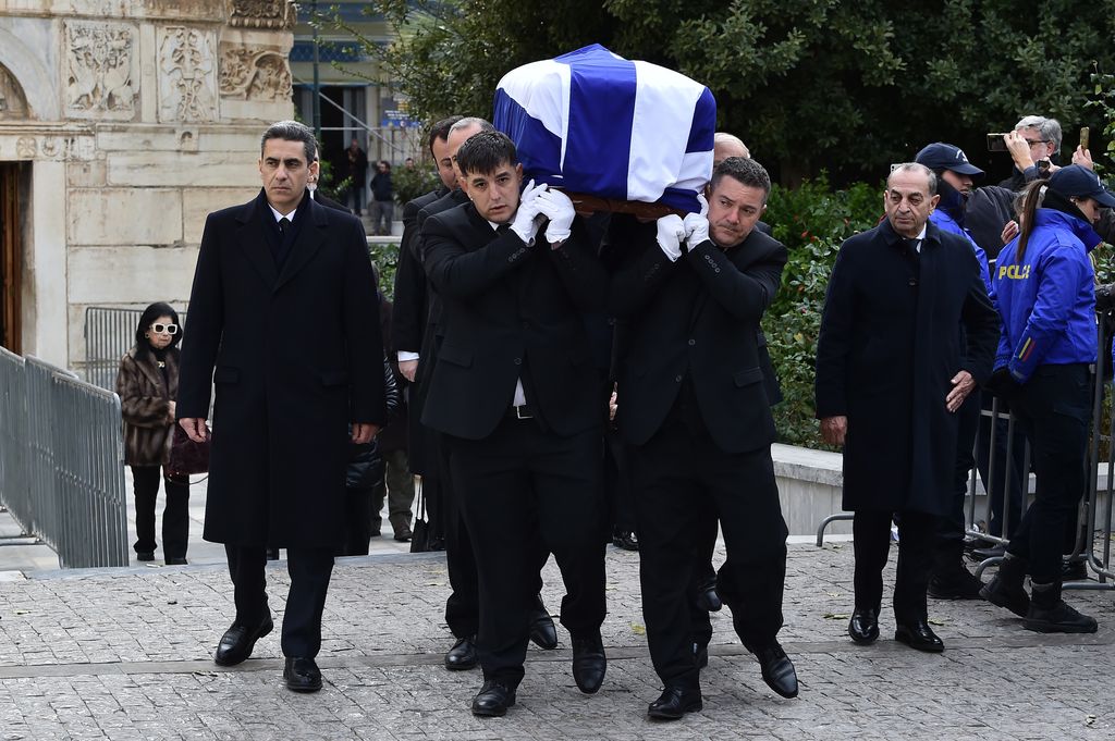 The coffin is carried into the funeral by men in black outfits