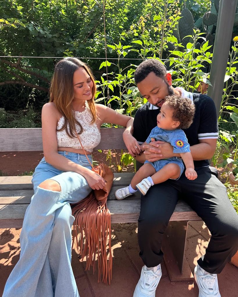 Chrissy Teigen and John Legend on a bench with baby son Wren 