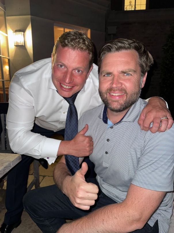 Thomas Skinner leaning over JD Vance and giving a thumbs up