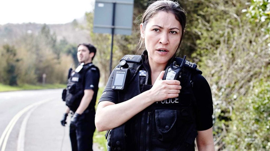 A scene from the show Cuffs featuring two police officers on the side of the road