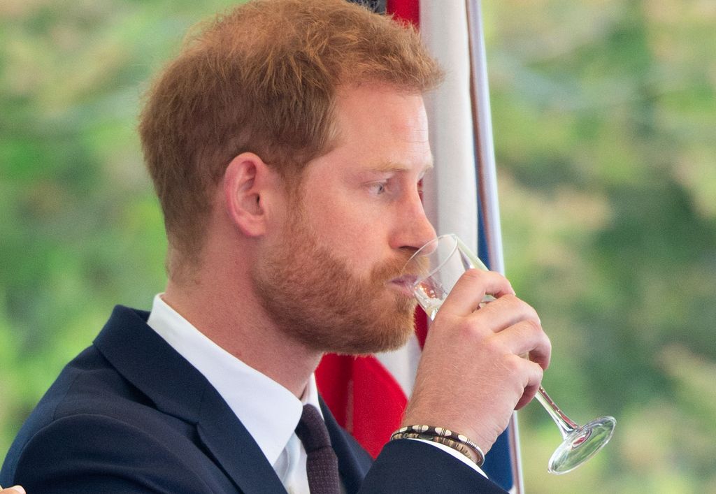 Prince Harry sipping champagne in a blue suit