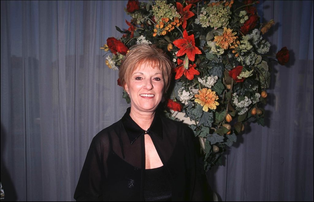 Claudette Dion in a black dress in front of a floral centrepiece