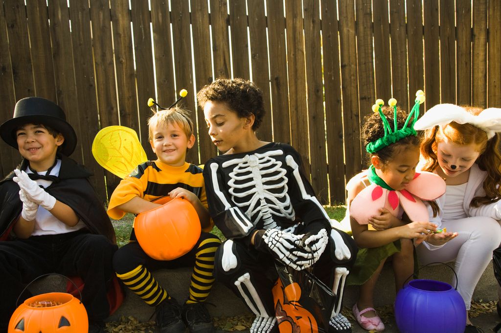 children in Halloween costumes sitting on sidewalk