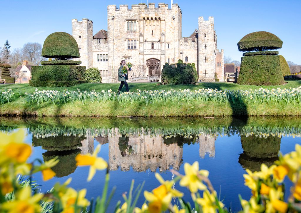 Shot of Hever Castle and its moat, alongside a woman carrying daffodils