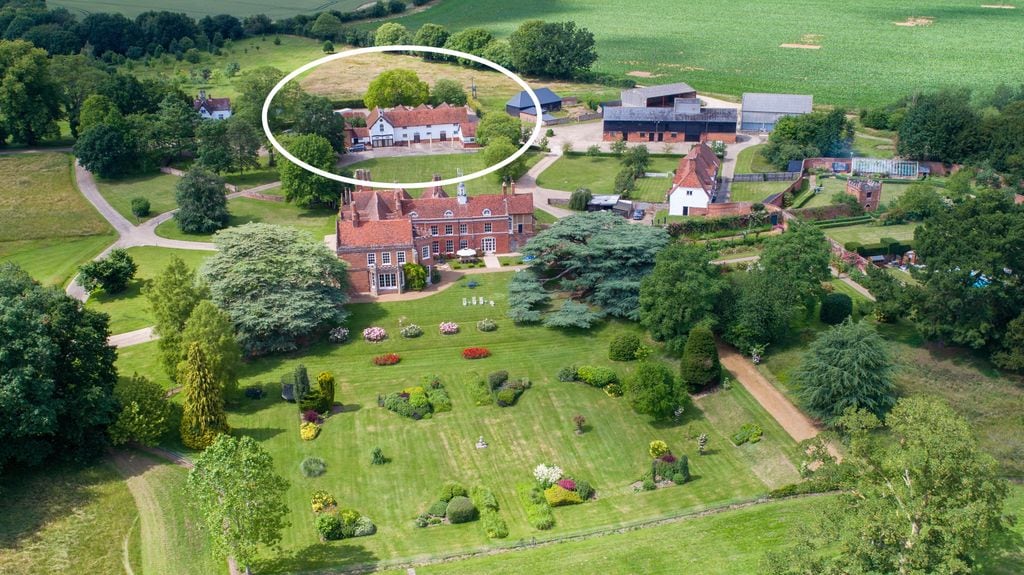 aerial view of manor house on leafy grounds with stable block circled