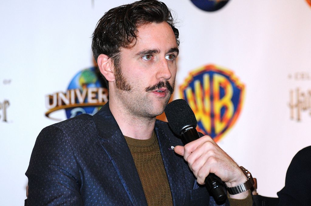Matthew Lewis with moustache holding mic