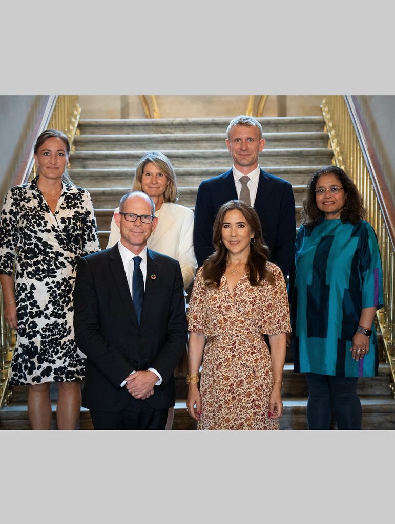 Queen Mary in brown and white dress posed with three women and two men