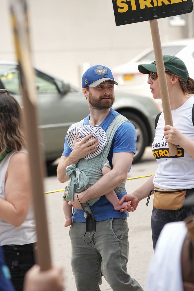 Daniel Radcliffe holding son as Erin Darke carries protest sign