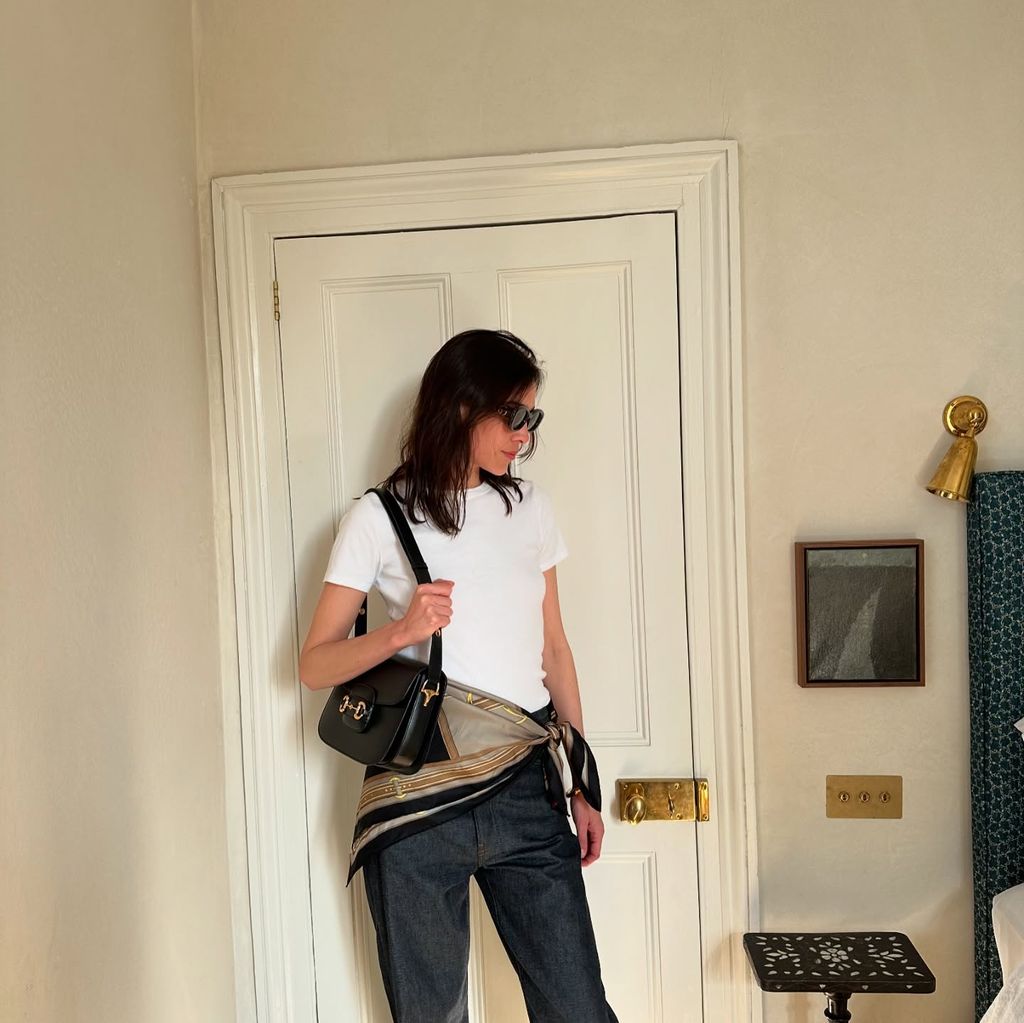 Alexa Chung poses in jeans, a white t-shirt and scarf tied around her hips