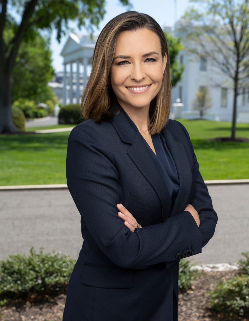 Woman in navy suit standing in front of the white house