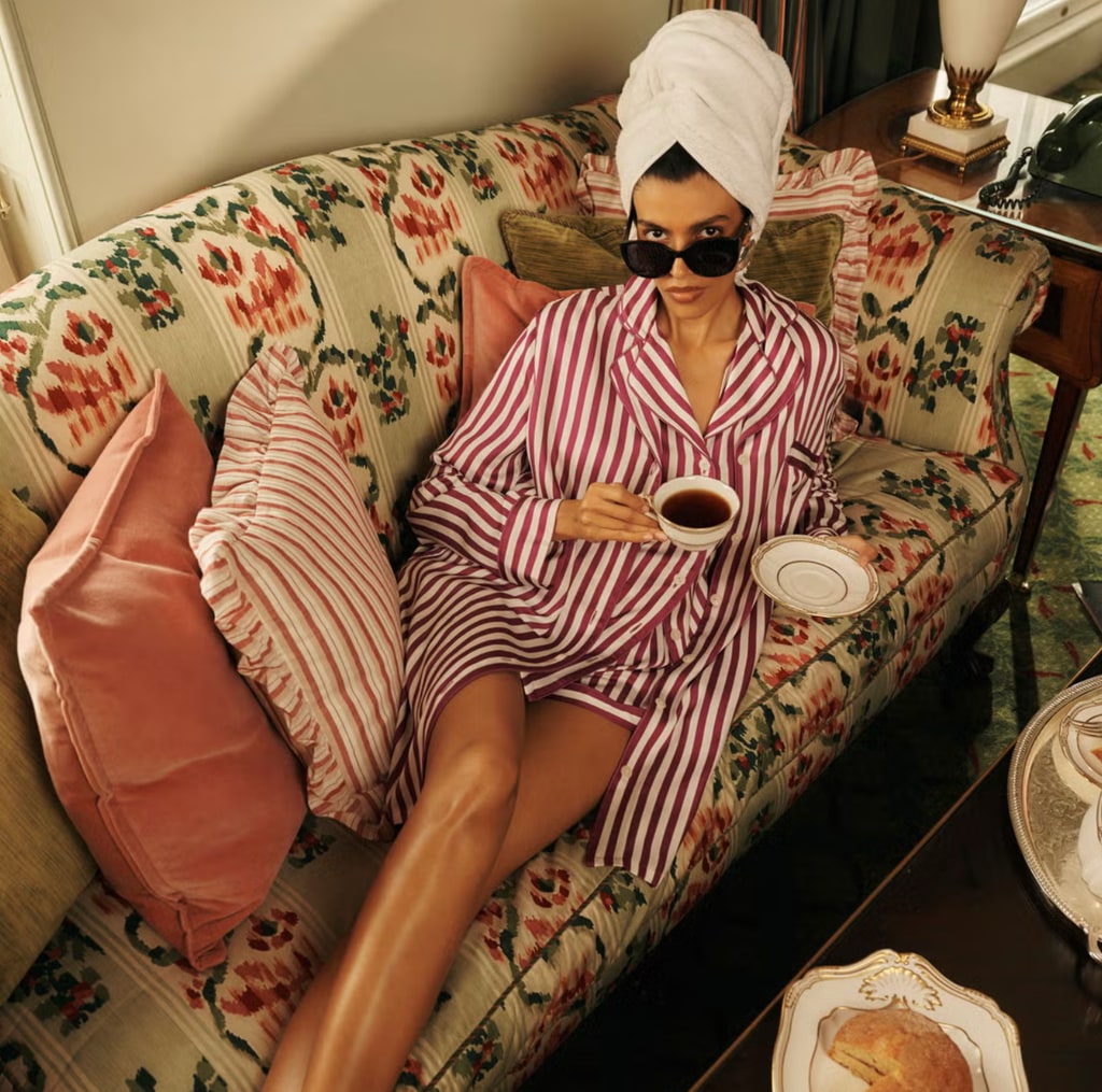 A model poses on a floral couch wearing a pair of striped pyjamas and a towel on her head