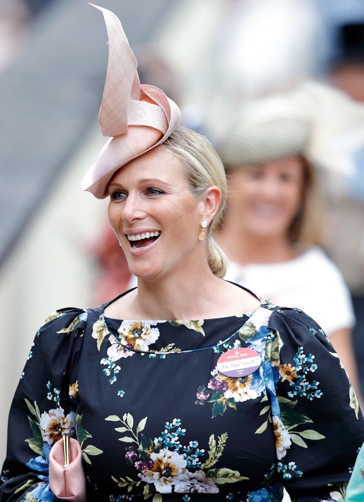 Zara Tindall smiling in black floral dress and pink hat