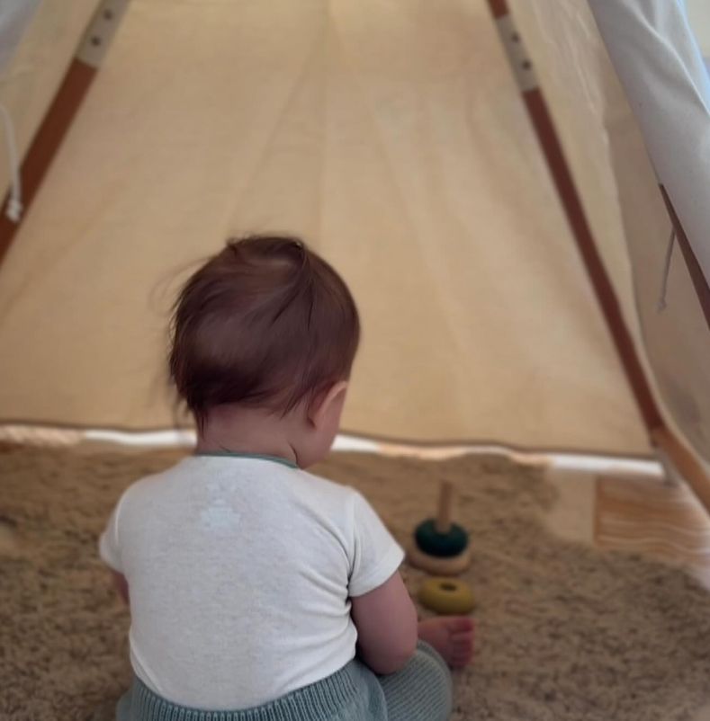 A baby sat in a tent