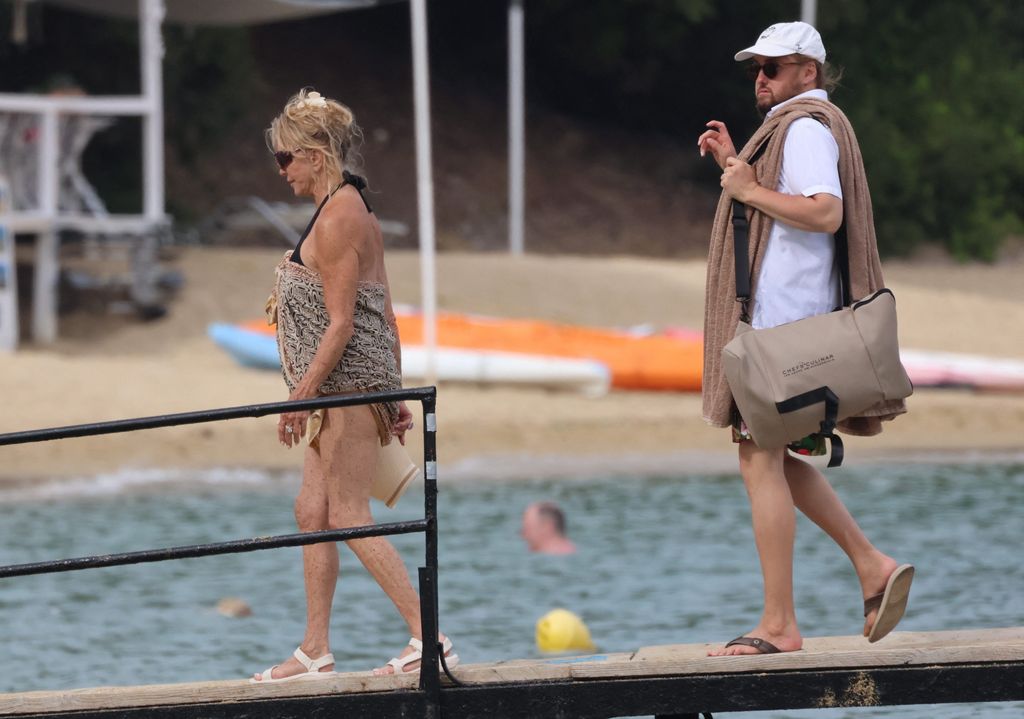 Goldie looked stylish in a black bathing suit and patterned sarong, accessorizing with a cute butterfly necklace and sun visor 