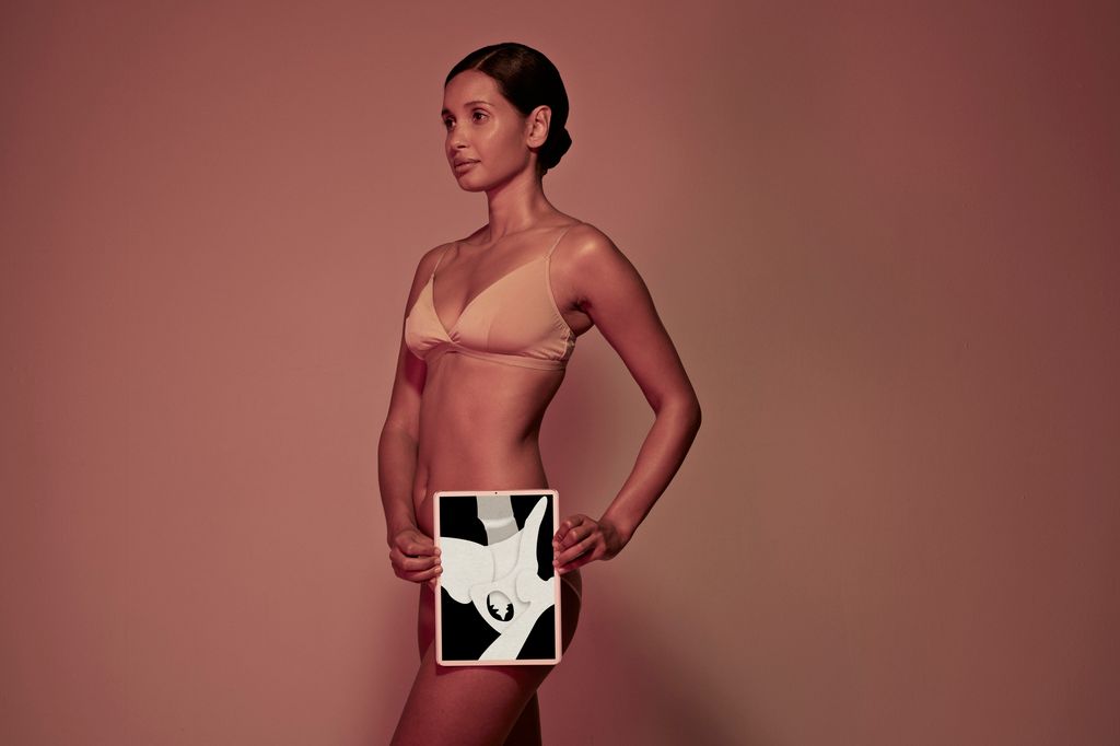 Female holding tablet in front of body to display coloured x-ray illustrations made out of hand made paper structures