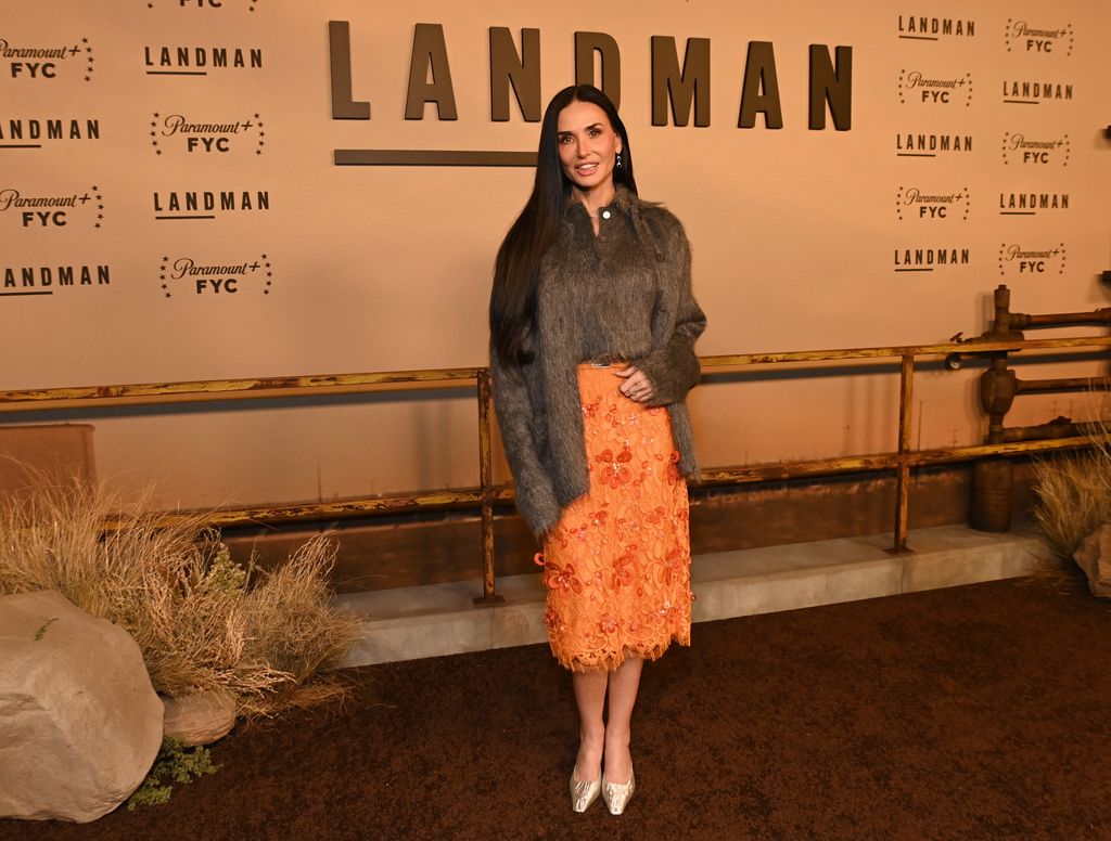 Demi Moore posed in grey cardigan and orange skirt