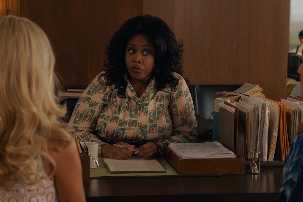 A woman with black hair and a shirt sits at a desk